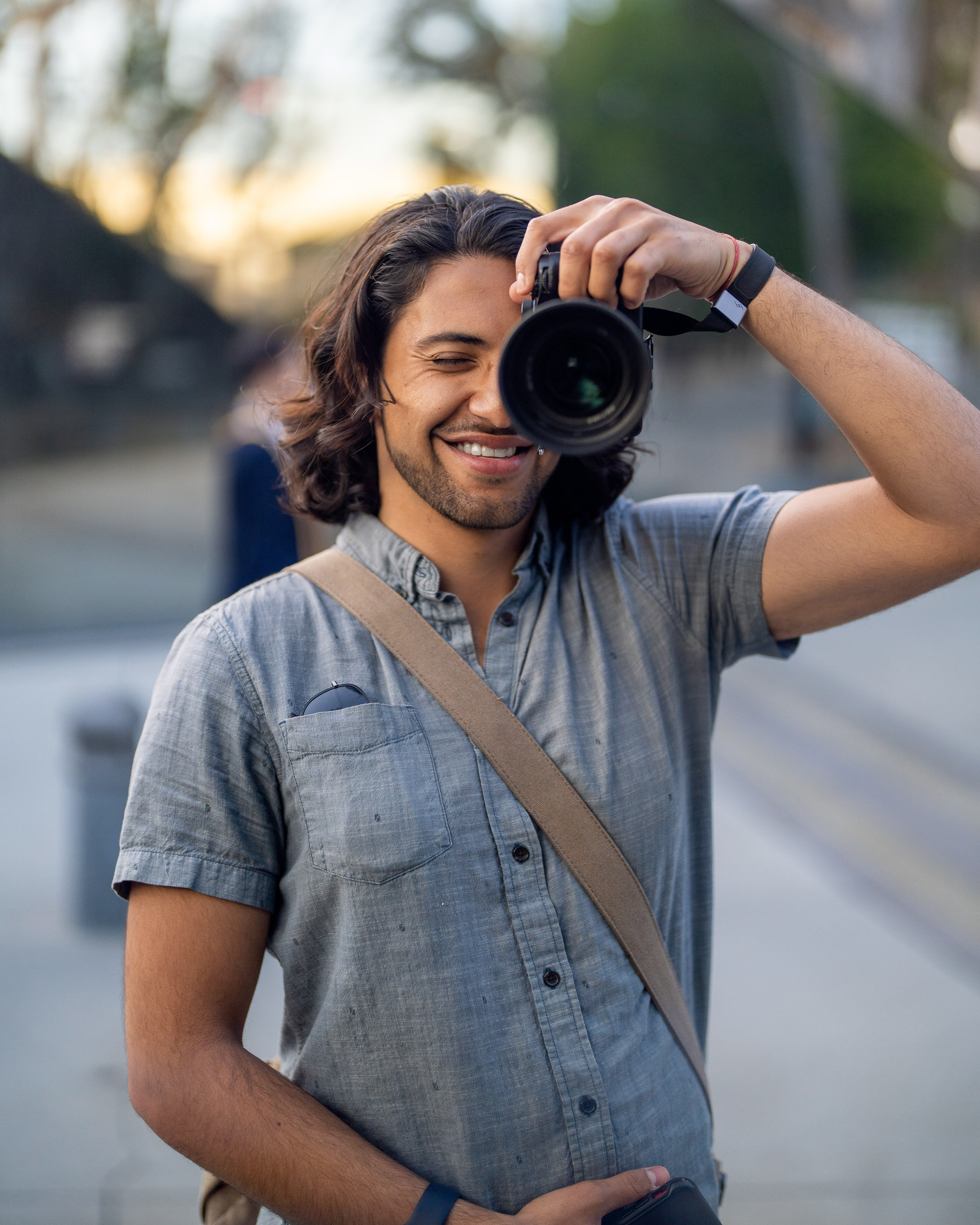 Photographer holding a camera and smiling during an outdoor photo session