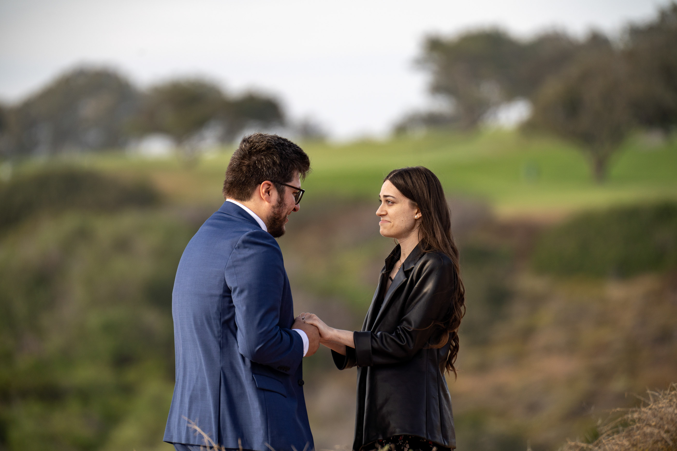 Couple holding hands and smiling together during an engagement session outdoors