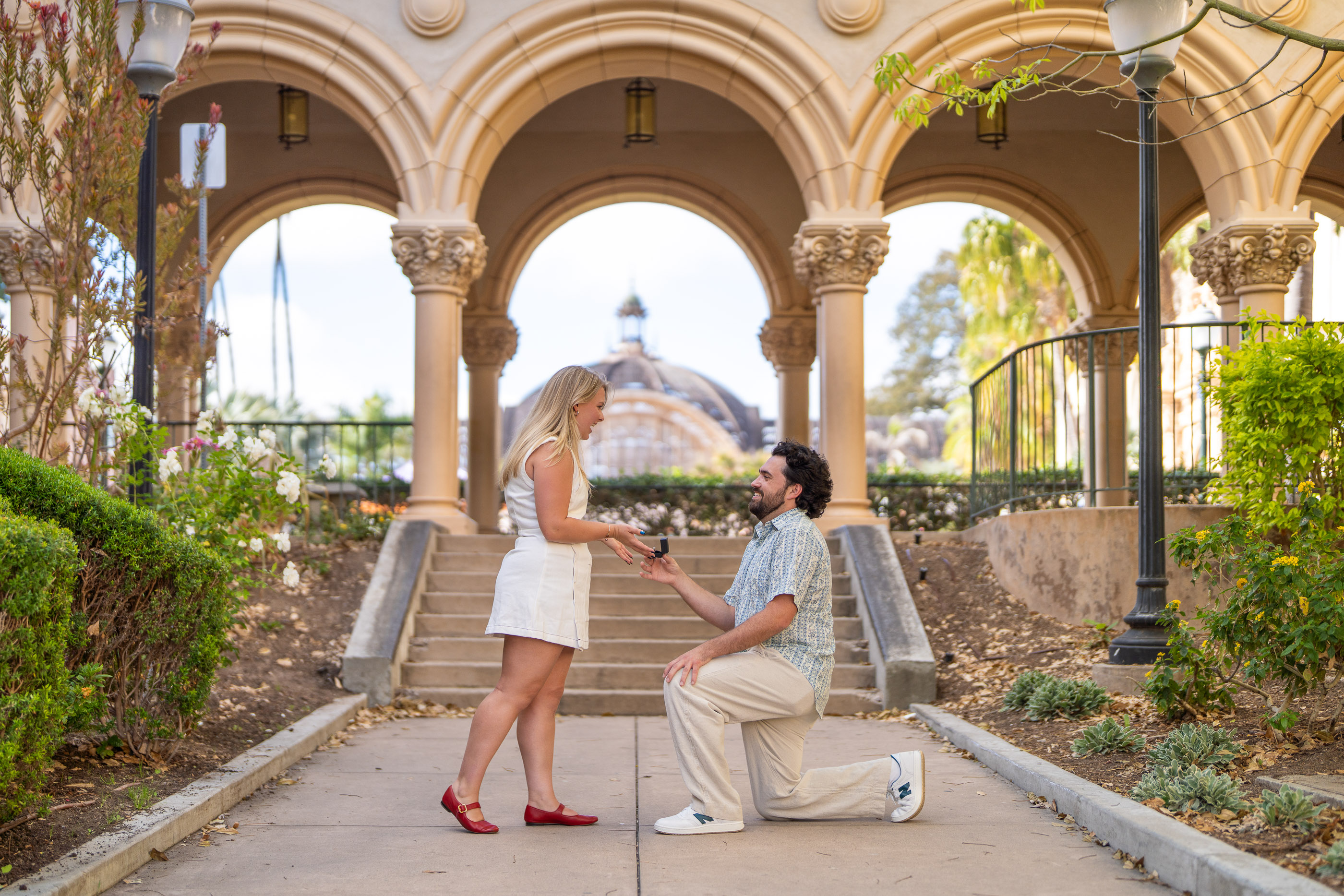 Couple celebrating an engagement beneath an arched outdoor walkway