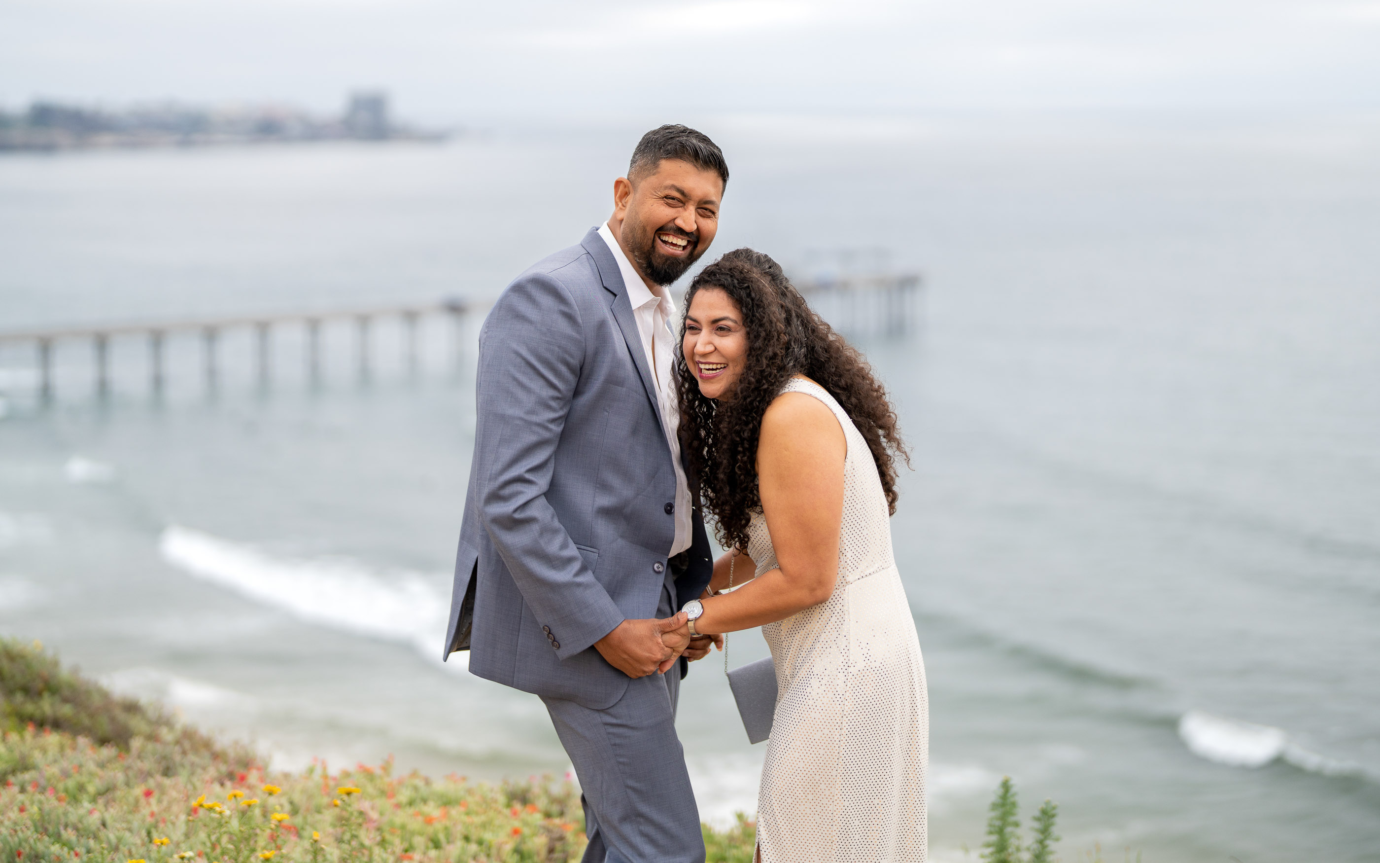 Couple embracing on a coastal overlook with the ocean behind them