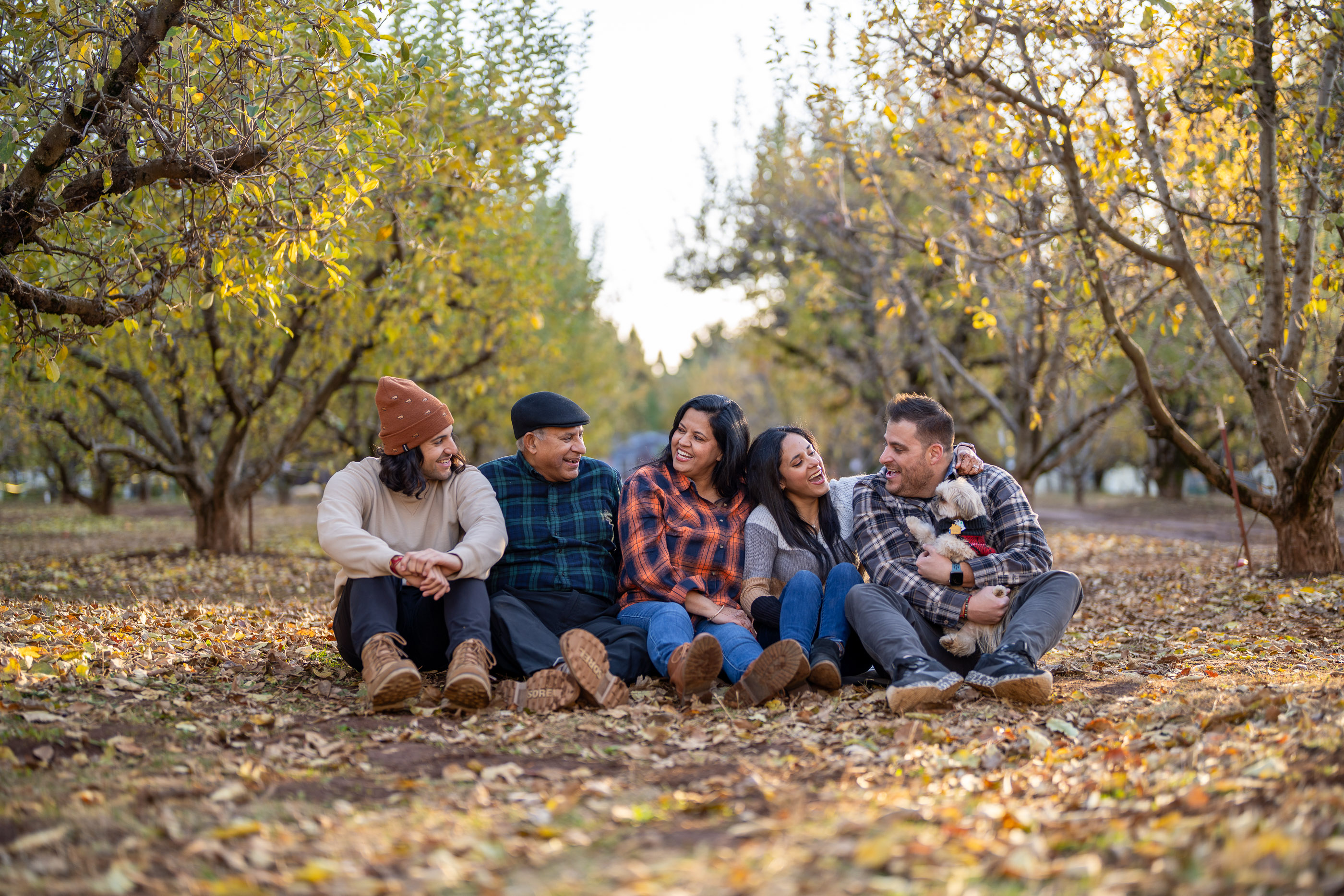 Family sitting together on fallen leaves in an autumn forest