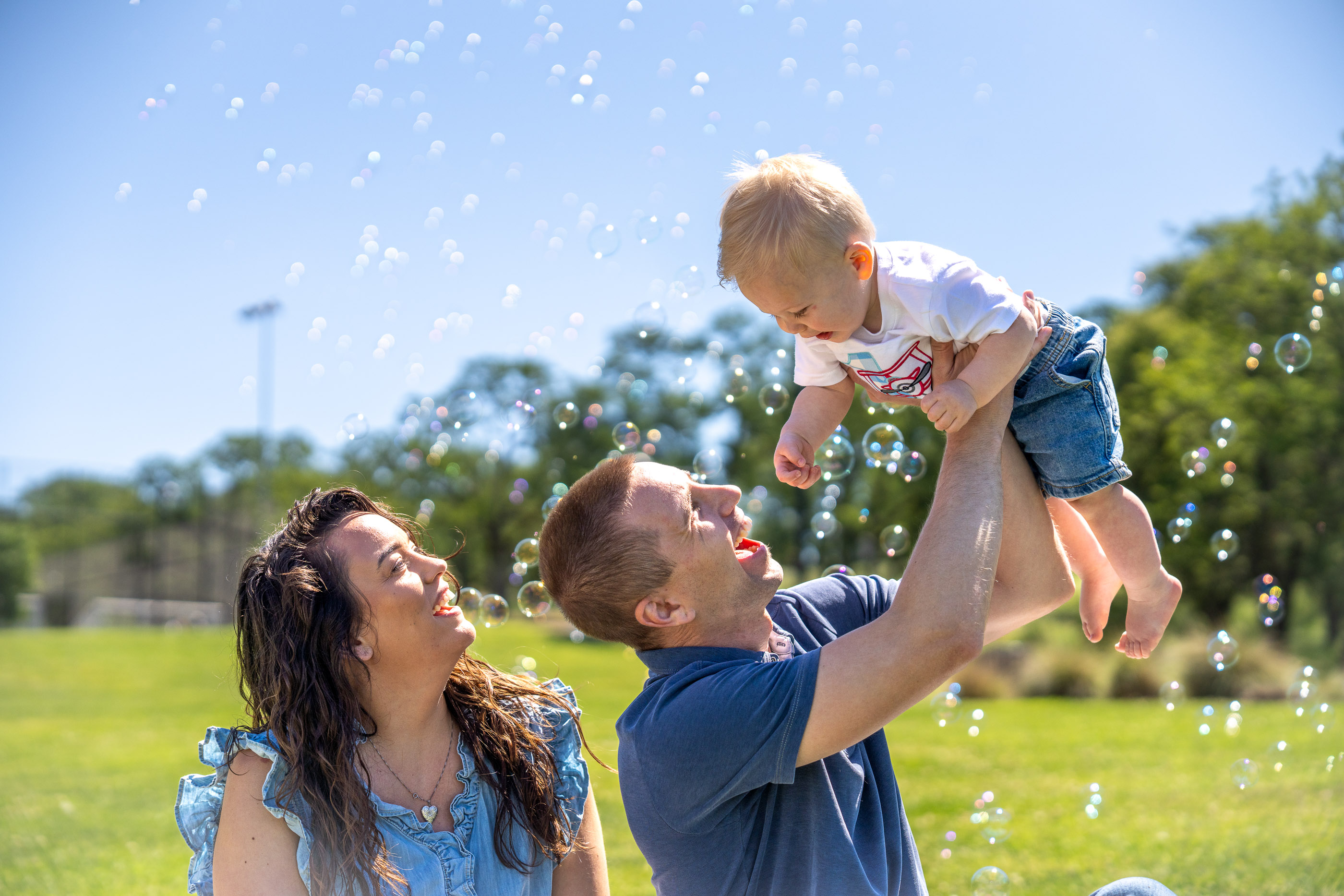 Parents lifting their young child into the air while playing outdoors