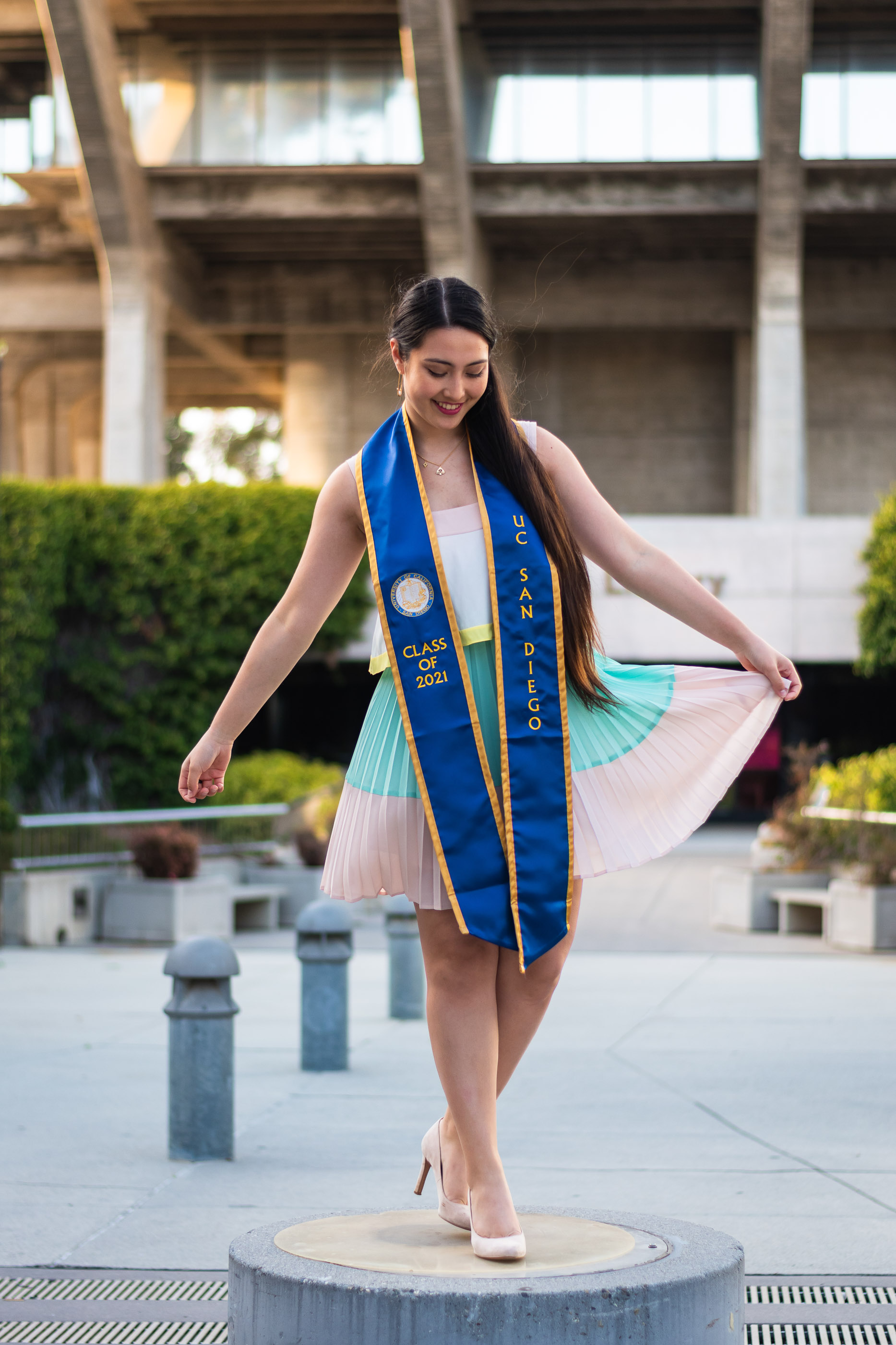 Graduate posing in cap and gown on a university campus
