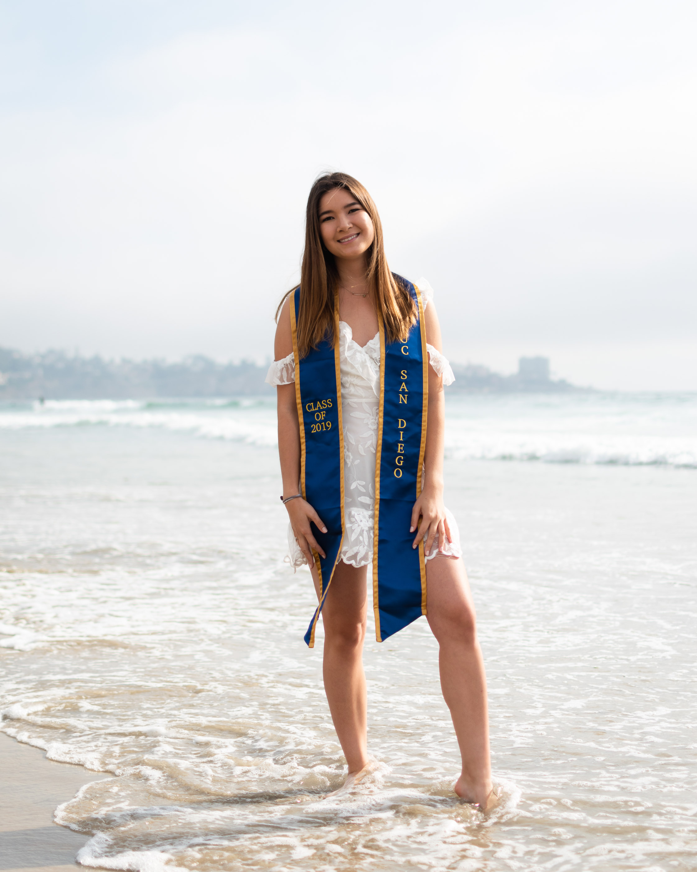 Graduate walking along the beach in cap and gown