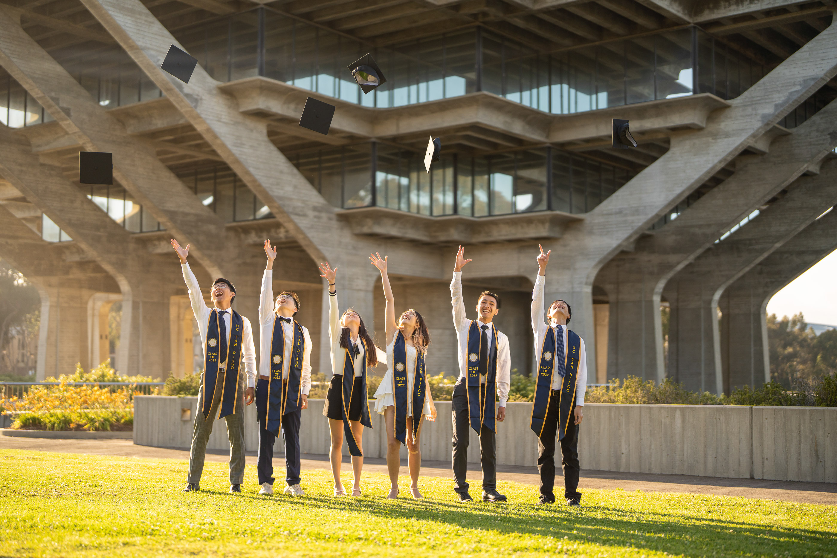 Group of graduates standing together beneath a university campus structure