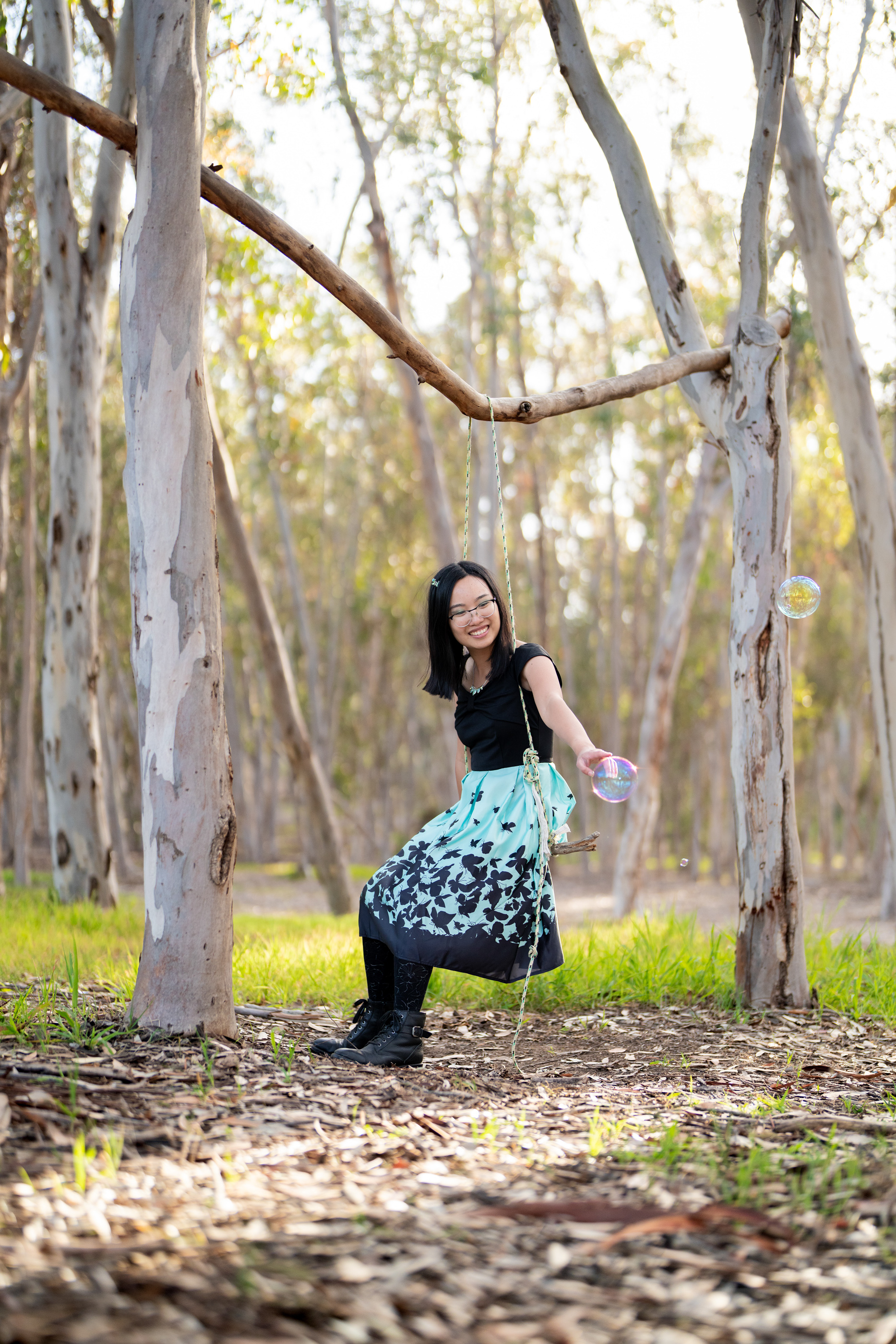 Woman sitting among eucalyptus trees and greenery in a peaceful forest setting.