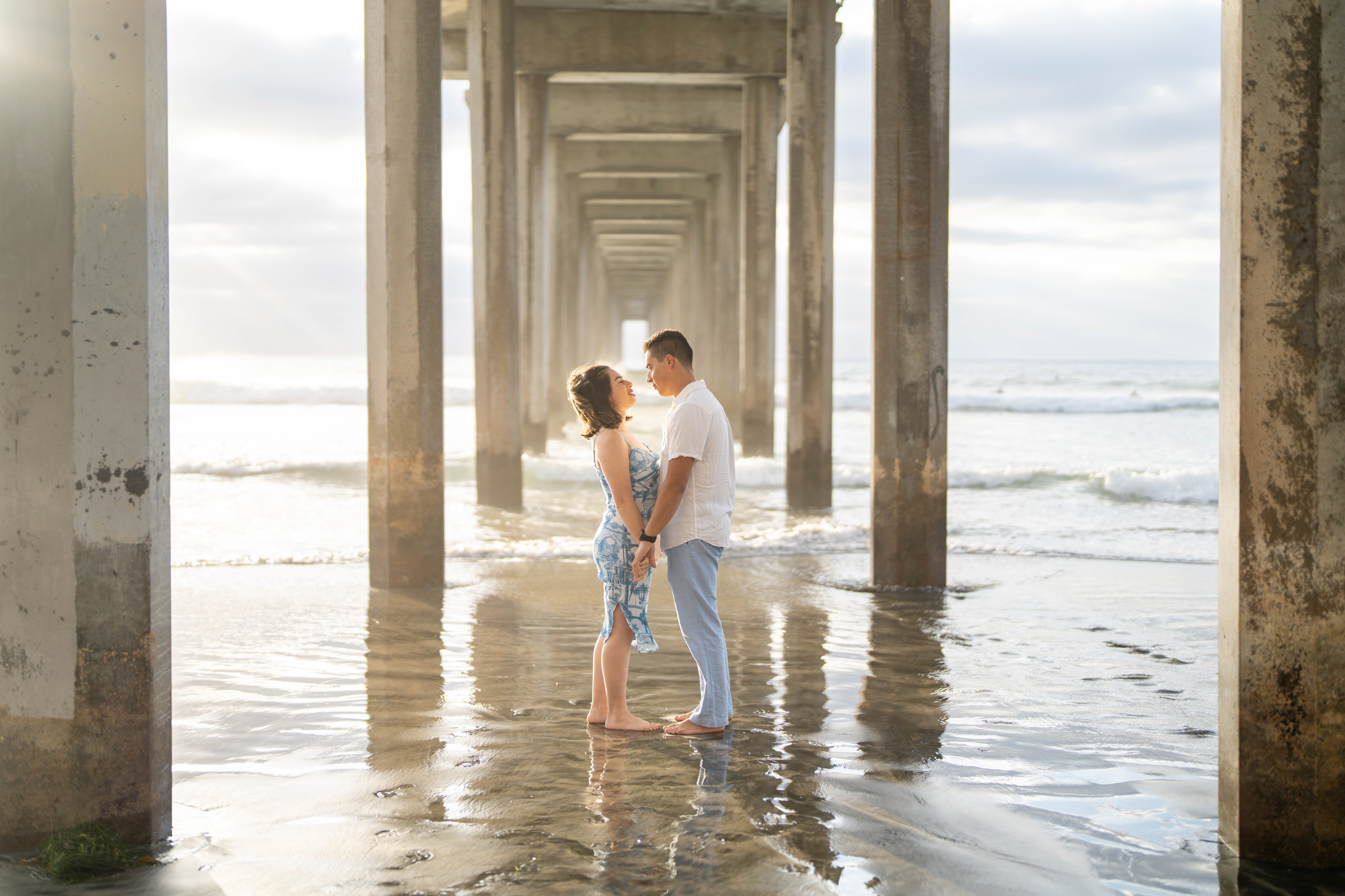 Couple standing together in shallow water beneath the Scripps Pier at La Jolla Shores.